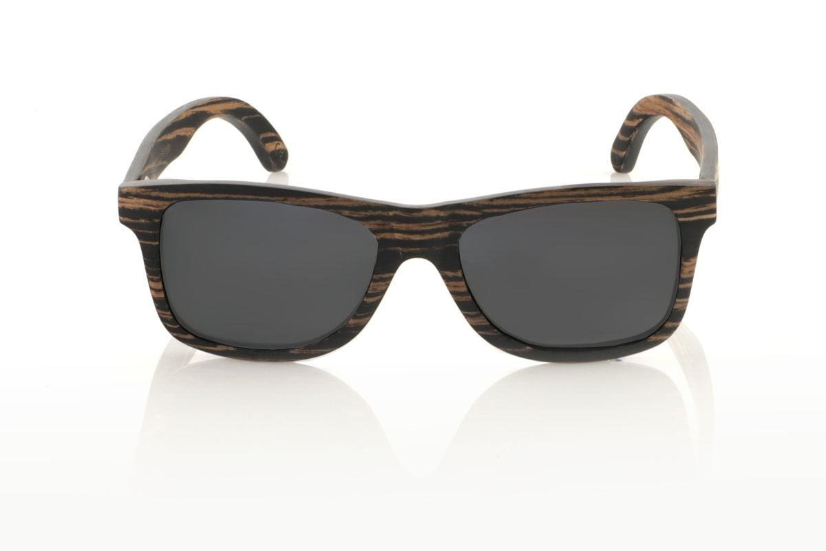 Gafas de Madera Natural de Ébano PARIS. Gafas de sol de madera PARIS presentan una silueta clásica con un toque más cuadrado y un tamaño medio, ideales para aquellos que buscan un estilo atemporal con un ajuste perfecto. Este modelo está íntegramente elaborado en madera de ébano africano, con un impresionante veteado en tonos negros y café, que aporta un aire de sofisticación. Con medidas de 148x45 y un calibre de 54, las PARIS son perfectas para quienes valoran la durabilidad y el diseño en sus accesorios. Este par no es solo un complemento para tu outfit, sino una declaración de estilo y aprecio por los detalles naturales y la artesanía de calidad. Venta al Por Mayor y Detalle | Root Sunglasses® 